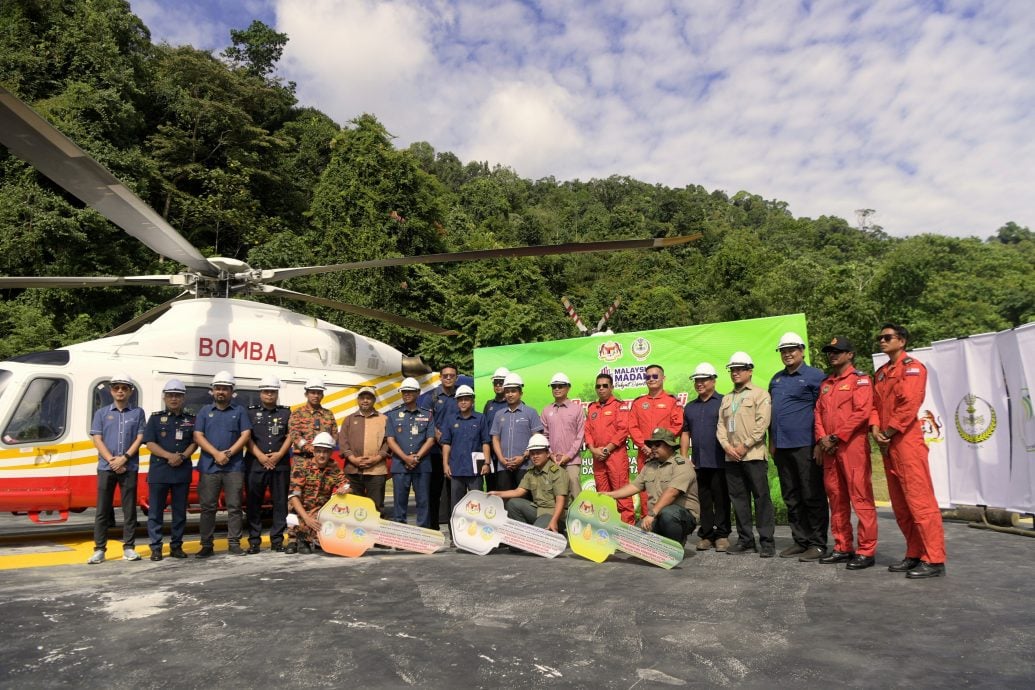 Penolong Pengarah (Seksyen Ladang Hutan dan Inovasi) Jabatan Perhutanan Perak, Mohamad Farhan Sukiman (tengah) bergambar selepas simbolik penyerahan replika kunci pada Program Ujikaji Tapak Pendaratan Helikopter dan Telaga Tiub bagi Menentang Kebakaran Hutan Negeri Perak di Hutan Simpanan Kekal Kenderong Daerah Hutan Hulu Perak hari ini.